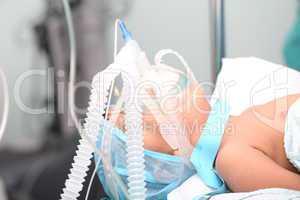 Unidentified boy with oxygen mask in the surgery. Focus in the m