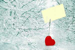 Heart holder with white paper over winter background