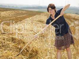 Women farmers with pitchfork works on the field