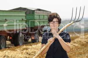 Women farmers with pitchfork works on the field