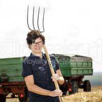 Women farmers with pitchfork works on the field