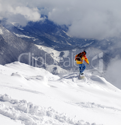 Snowboarder on off-piste slope an mountains in haze