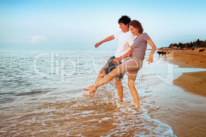 Boy and girl having fun sprinkled sea waves