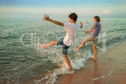 Boy and girl having fun sprinkled sea waves