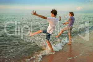 Boy and girl having fun sprinkled sea waves
