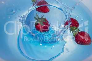 strawberries falling into water with water splashes