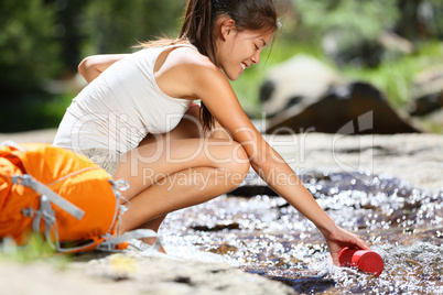 Hiker woman taking water in river in Yosemite