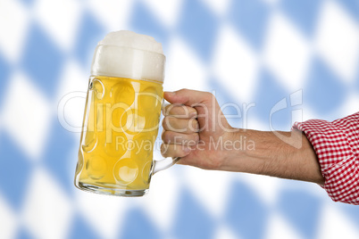 Man in traditional Bavarian shirt holds mug of beer