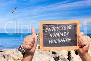 Daumen hoch. Tafel mit Text: Enjoy your Summer Holidays