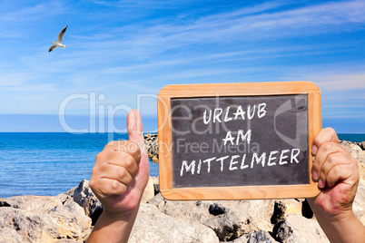 Daumen hoch. Tafel mit Text: Urlaub am Mittelmeer