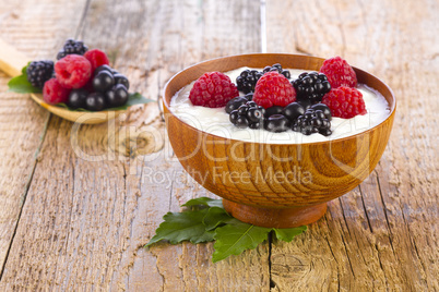 yogurt with wild berries in wooden bowl