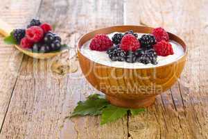 yogurt with wild berries in wooden bowl