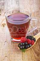 Fruit red tea with wild berries in wooden spoon