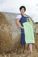 Woman standing on straw bales and enjoys the outdoors
