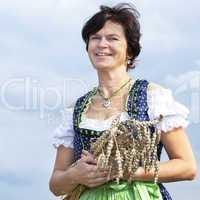 Bavarian woman in dirndl holds heads of grain in wheat field