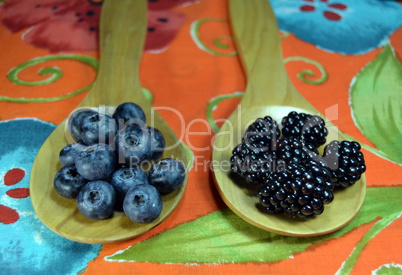 Blueberries and blackberries in wooden spoons