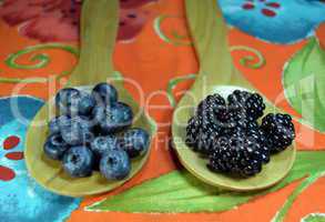 Blueberries and blackberries in wooden spoons