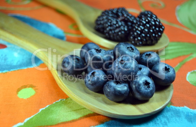 Blueberries and blackberries in wooden spoons