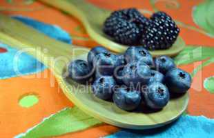 Blueberries and blackberries in wooden spoons