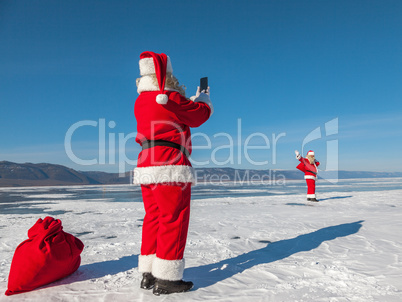 Santa Claus shoot on a smartphone of other Santa, walking on the