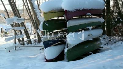Eight boats turned upside down are covered with snow