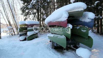 Two sets of boats piled upside down with snow