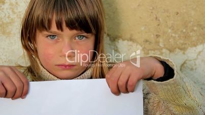 Boy holding a sheet of paper.Child holding a sheet of paper.Against the background of an old wall