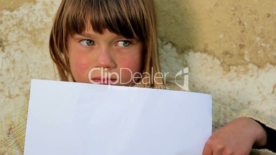 Boy holding a sheet of paper.Child holding a sheet of paper.Against the background of an old wall