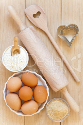 Mehl, Zucker, Eier und Backutensilien auf Holztisch