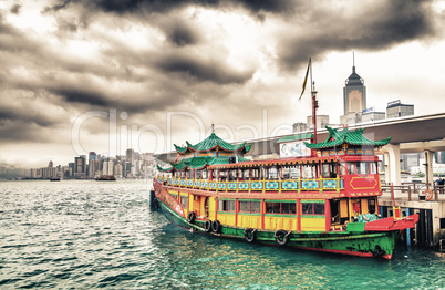 Hong Kong port. Colourful old cruise ship with city skyline on b