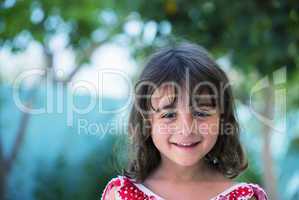 Happy baby girl with red dress smiling outdoor, trees and meadow