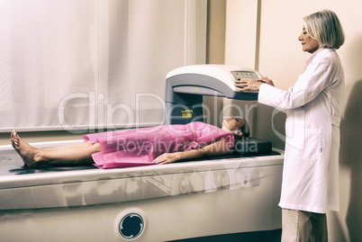 Female doctor examining woman in 40s at Bone Densitometer Machin