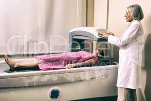 Female doctor examining woman in 40s at Bone Densitometer Machin