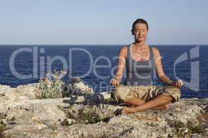 Yoga posture on rocks near the ocean