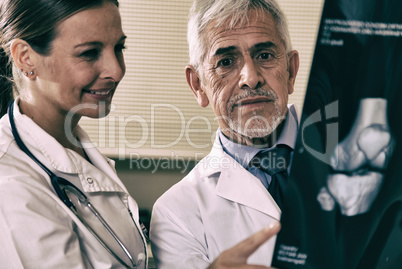 Senior expert male doctor analyzing x-ray scan with his female a