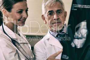 Senior expert male doctor analyzing x-ray scan with his female a