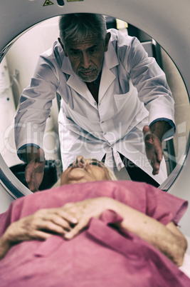 Senior male doctor examining woman in 70s with CT scanner
