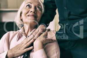 Senior woman on wheelchair taking her husband's hand