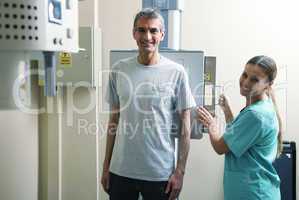 Happy female doctor ready to screen male patient at xray machine