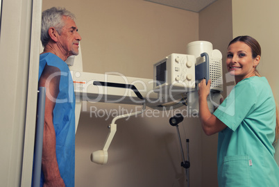 Smiling female doctor scanning man in 70s with x-ray device