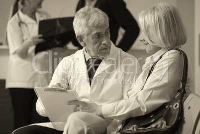 Senior male doctor showing medical results to his female woman p