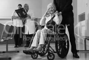 Senior woman on wheelchair with her husband and doctors analyzin
