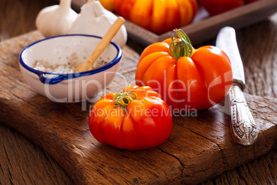 Fleischtomaten mit Messer und Salz auf Schneidebrett