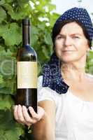 Woman holding bottle full of wine in vineyard
