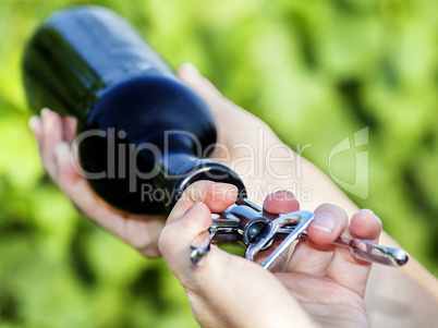 Hand opening bottle of wine in the vineyard