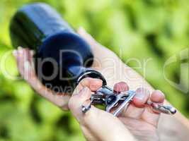 Hand opening bottle of wine in the vineyard