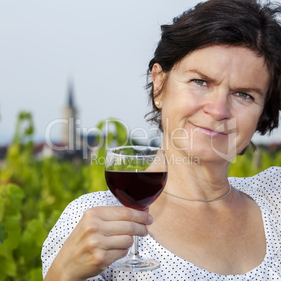 Woman with glass of red wine in vineyard