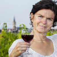 Woman with glass of red wine in vineyard