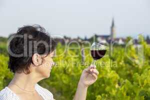 Woman with glass of red wine in vineyard