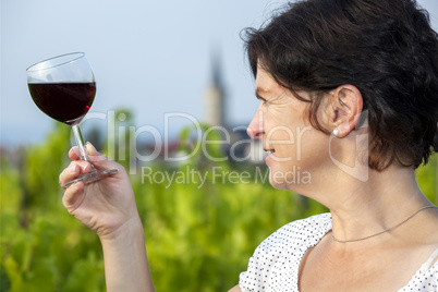 Woman with glass of red wine in vineyard